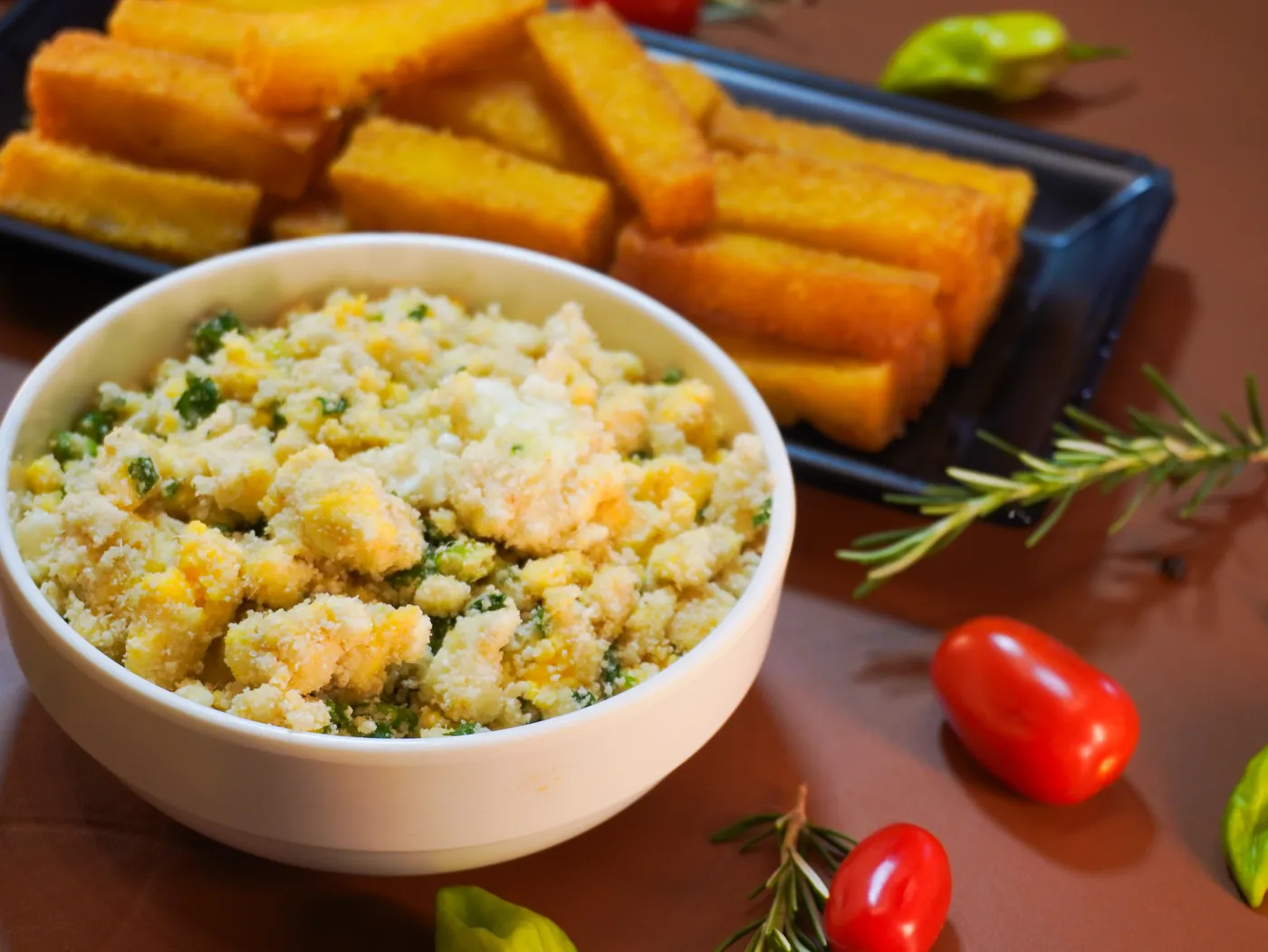 Farofa de ovos em tigela branca, com polenta frita ao fundo